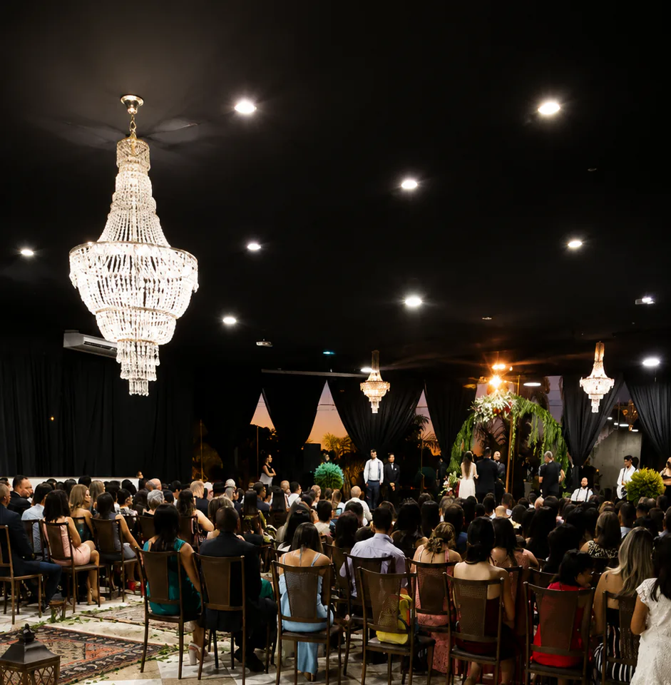 Salão lotado sob lustres de cristal, com o palco ao fundo